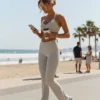 Model wearing Manual Product - Casually checking a smartphone while walking or sitting, holding a to-go coffee cup, distracted everyday movement at Mediterranean beach promenade in Tel Aviv, soft waves, casual passersby, authentic outdoor scene